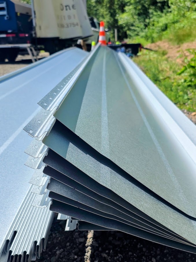 Close up of dark standing seam metal roof ridge cap detail against overcast sky