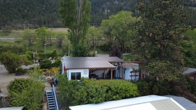 Aerial view of standing seam metal roof on residential building surrounded by trees and mountains