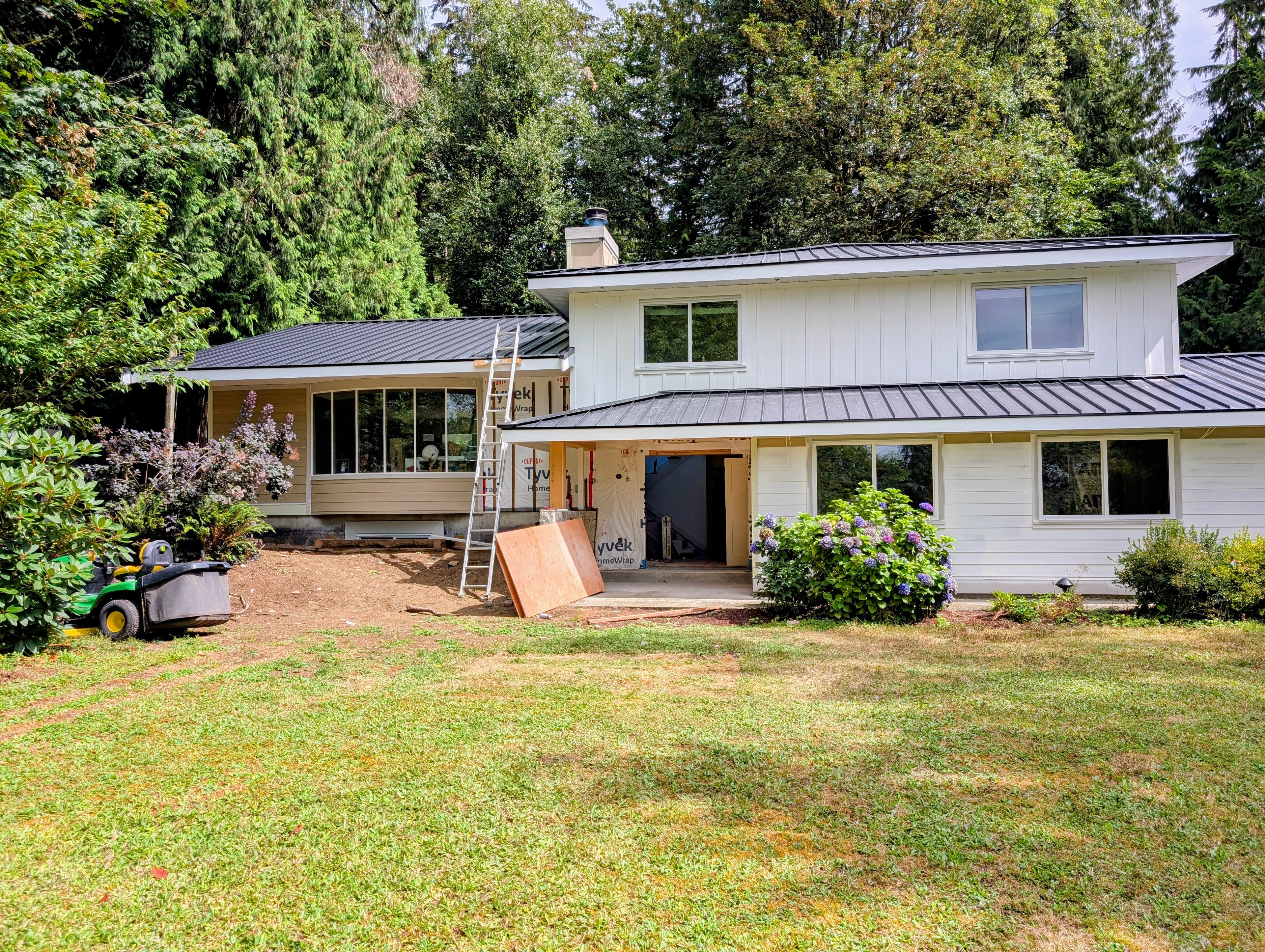 Residential home renovation with white siding and dark metal standing seam roof