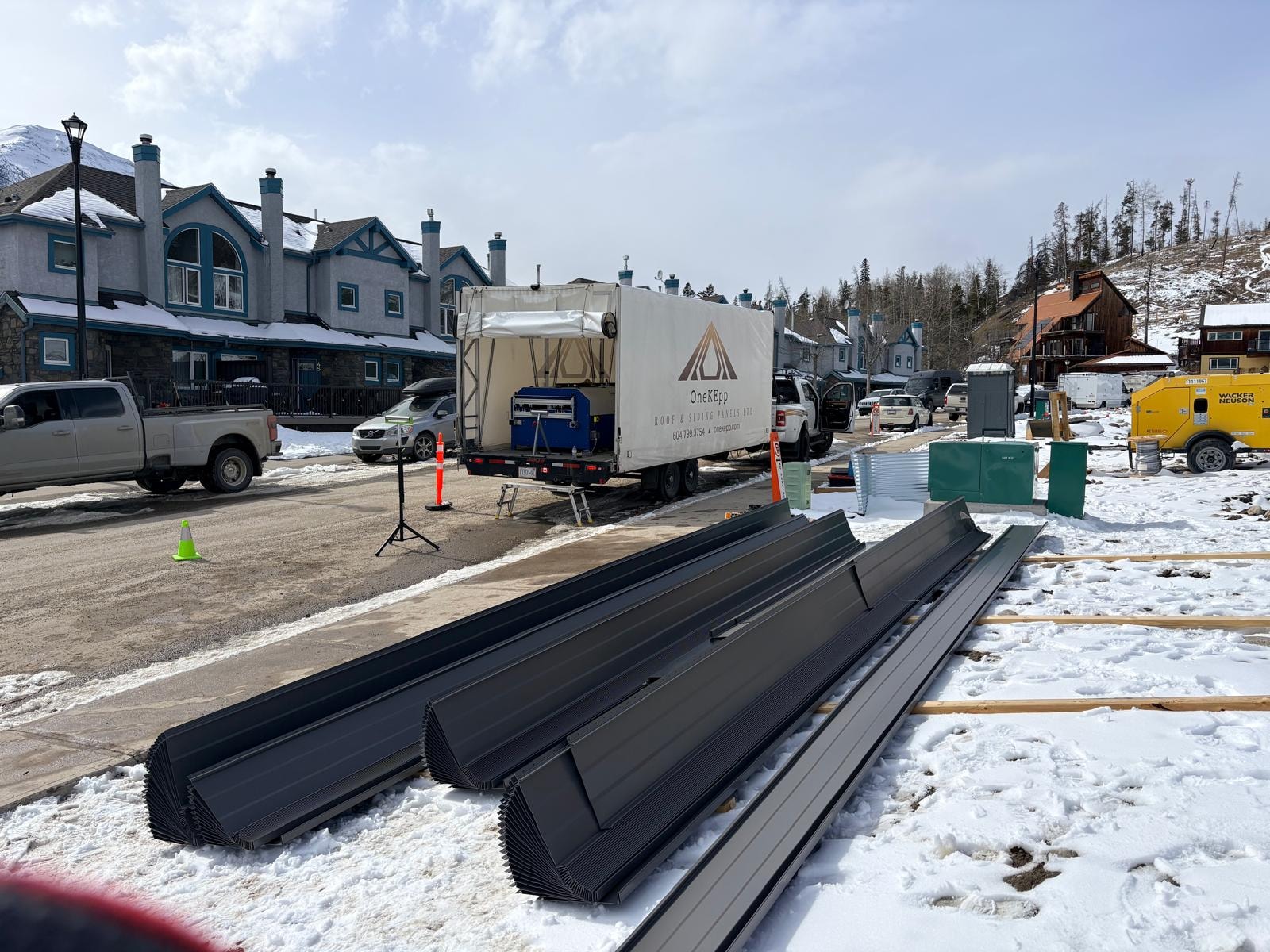 OneKEpp truck on site with fresh dark metal panels laid out in snow mountain town