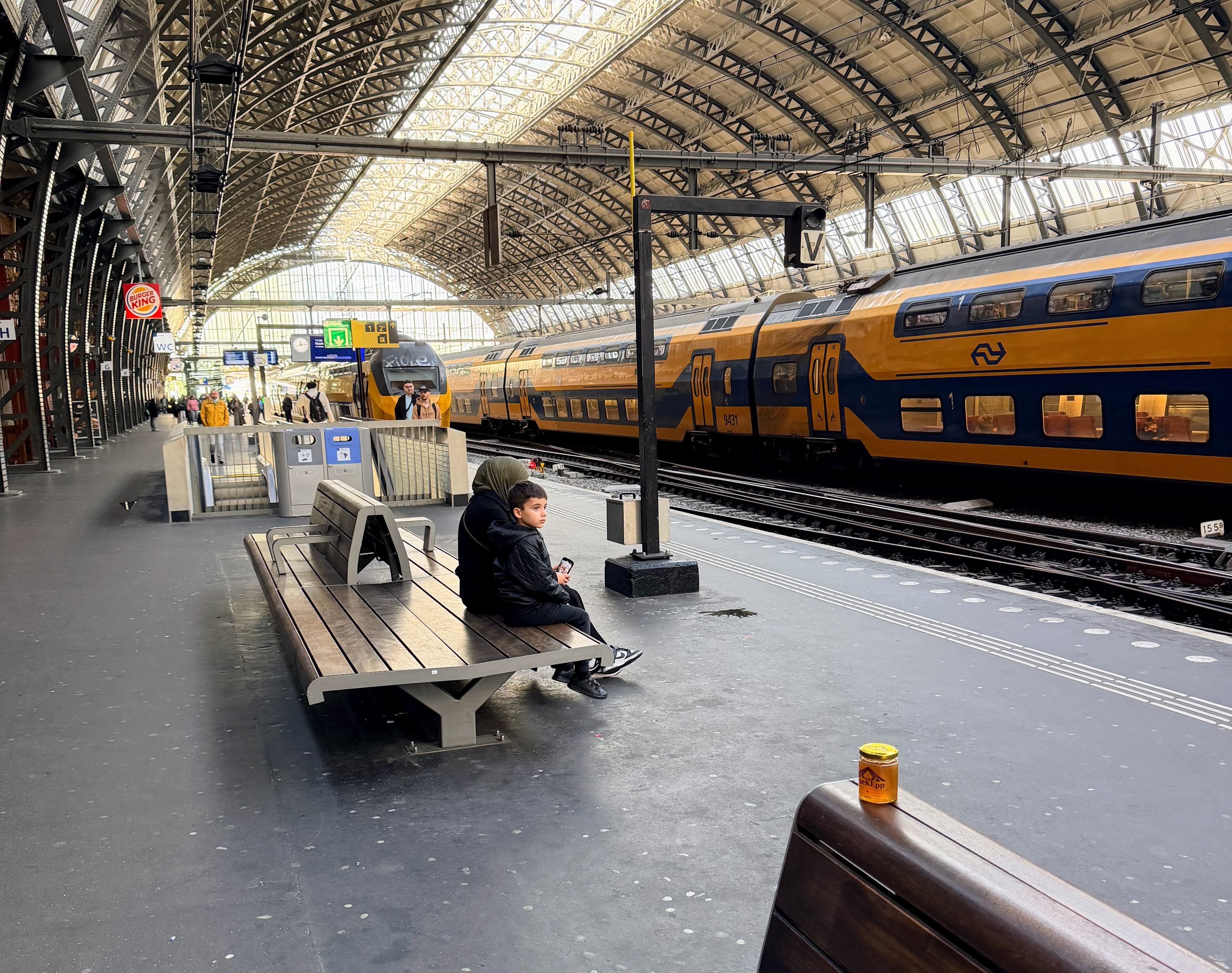 OneKEpp honey jar on a platform bench at Amsterdam Centraal station with a Dutch intercity train