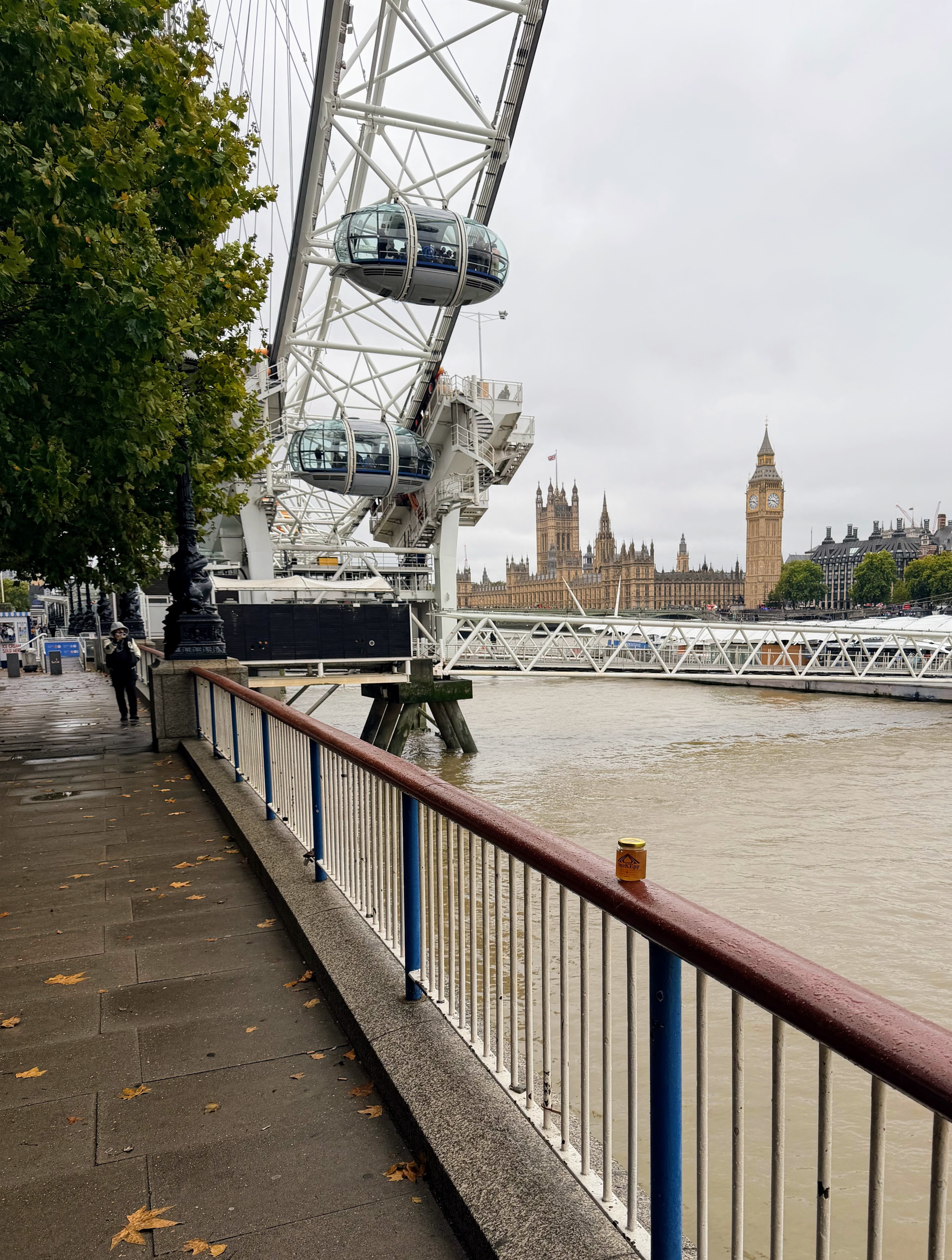 OneKEpp honey jar on the South Bank railing with the London Eye and Parliament visible